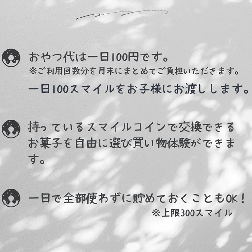 おやつ代は1日100円です。もっているスマイルコインで交換できるお菓子を自由に選び買い物体験ができます。1日で使わず貯めておくこともOK！